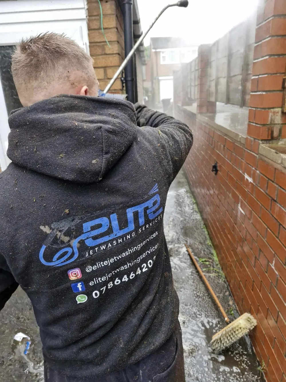 Elite Jetwashing Services branded workwear on a wall cleaning job